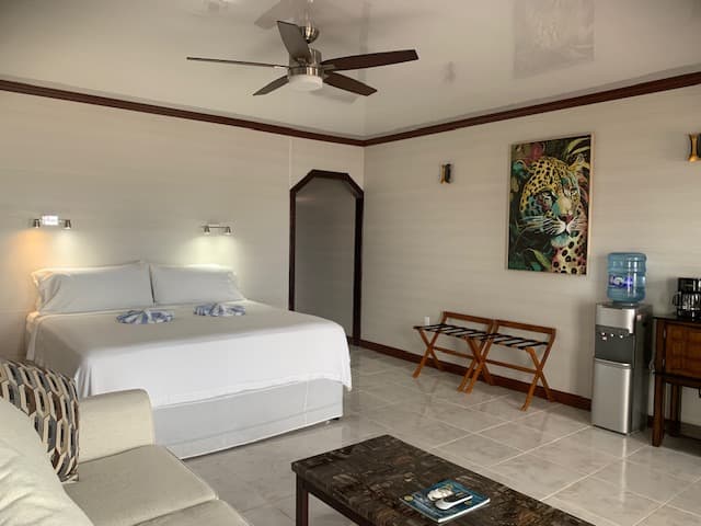 A spacious hotel room featuring a king-sized bed, seating area, and colorful artwork on the wall.