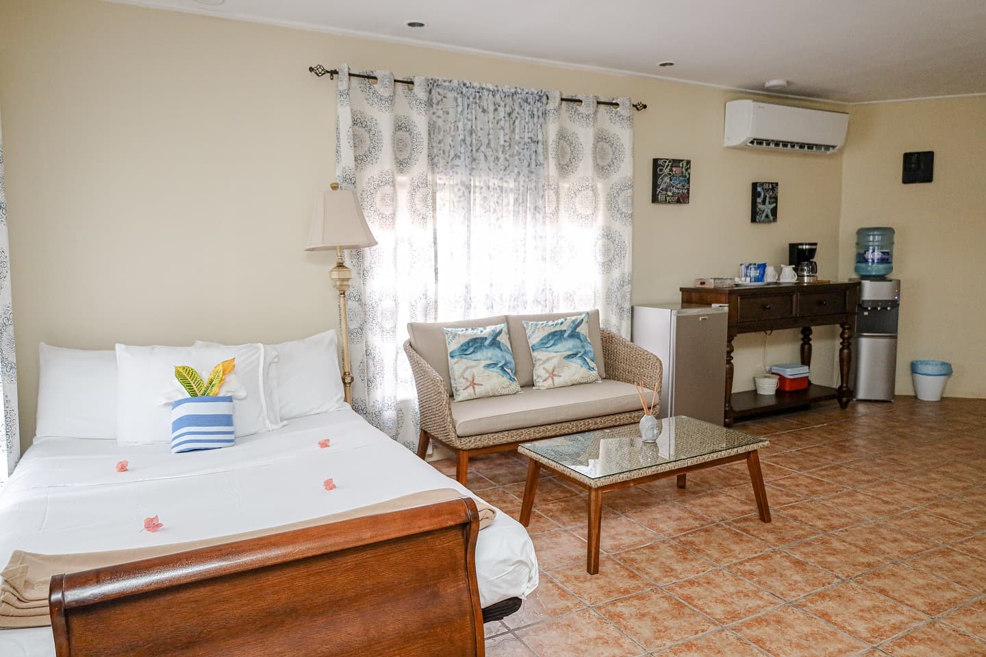 Cozy room featuring a bed, a sofa, a coffee table, and a kitchenette with a water dispenser.