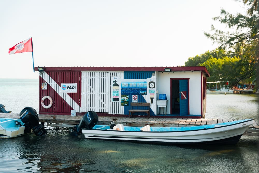 A colorful dockside building with a boat and flags, serving as a diving center.