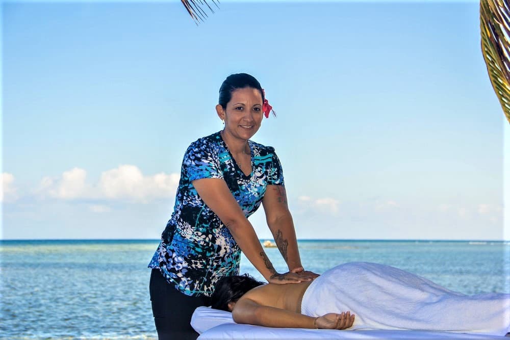 A masseuse provides a massage outdoors by the ocean.