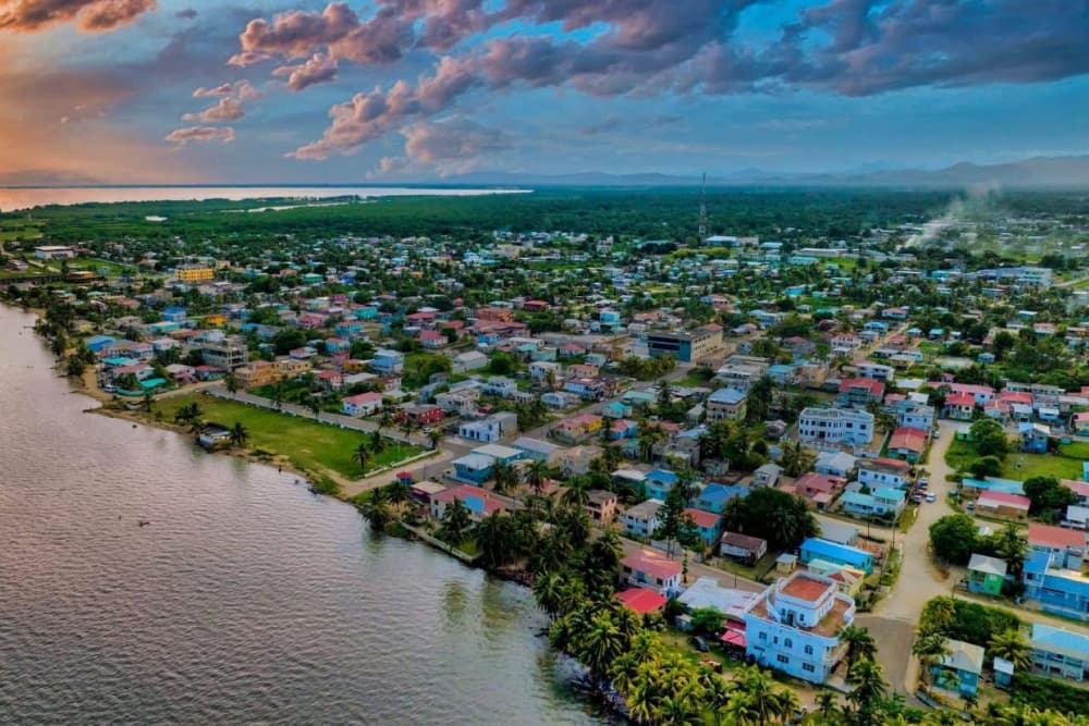 Aerial view of a coastal town surrounded by lush greenery and water at sunset.
