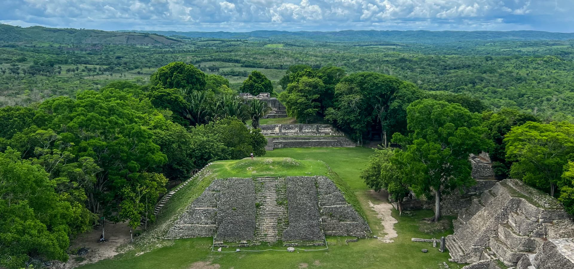 Aerial view of ancient stone ruins surrounded by lush greenery and rolling hills.