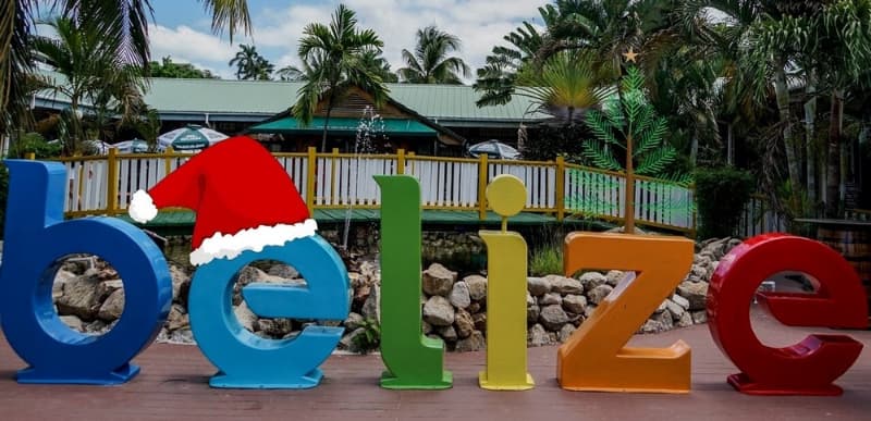 Colorful "Belize" letters adorned with a Santa hat, set in a tropical landscape. Colorful "Belize" letters adorned with a Santa hat, set in a tropical landscape.
