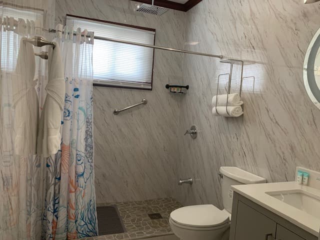 A modern bathroom featuring a glass shower, white toilet, and a vanity with toiletries.