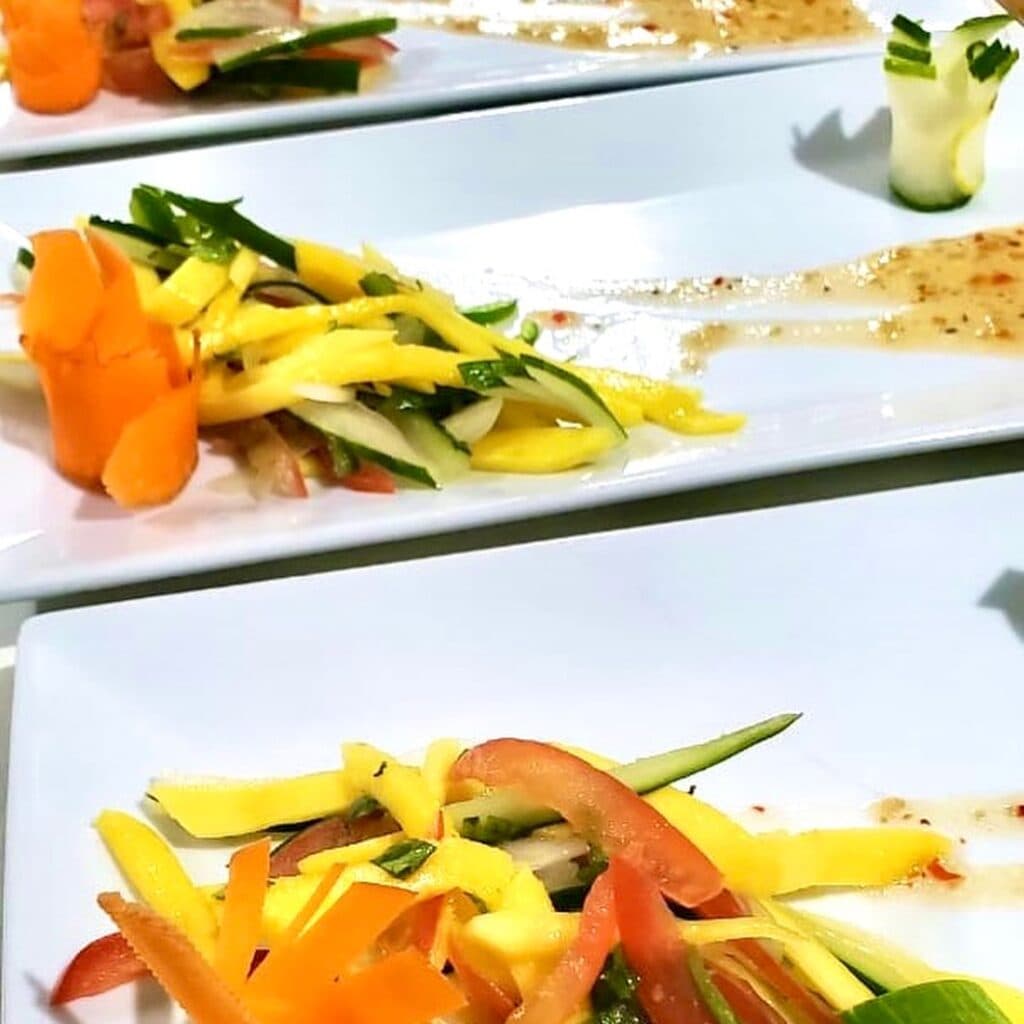 Colorful vegetable garnishes artfully arranged on white plates.