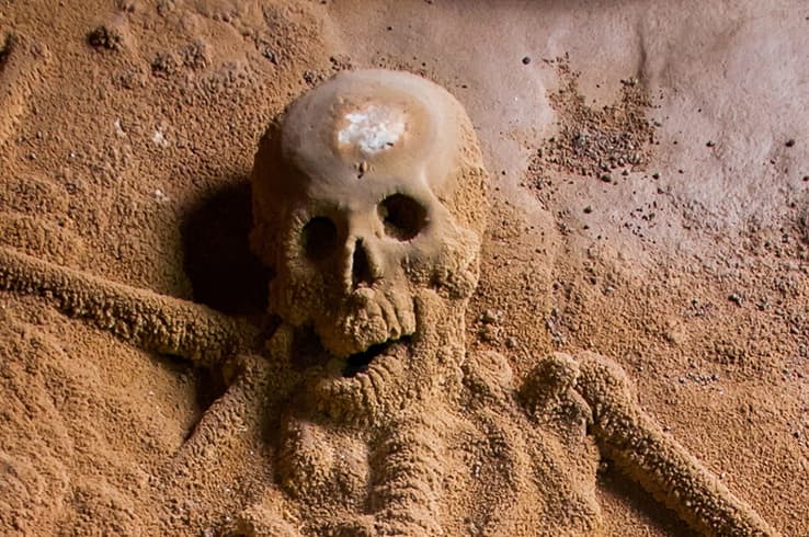 A skeleton partially buried in sandy soil.