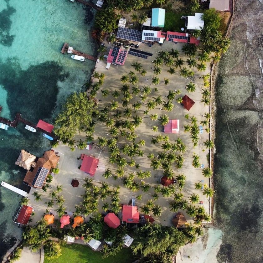 Aerial view of a tropical resort with palm trees, colorful buildings, and turquoise waters. Aerial view of a tropical resort with palm trees, colorful buildings, and turquoise waters.