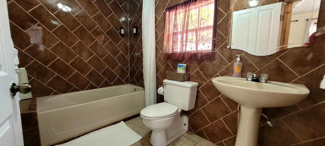 A bathroom featuring a bathtub, toilet, and sink against tiled walls.