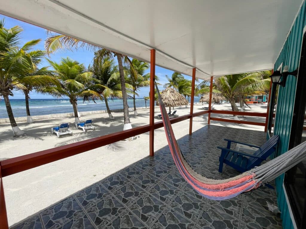 View of a beachside patio with a hammock and palm trees overlooking the ocean.