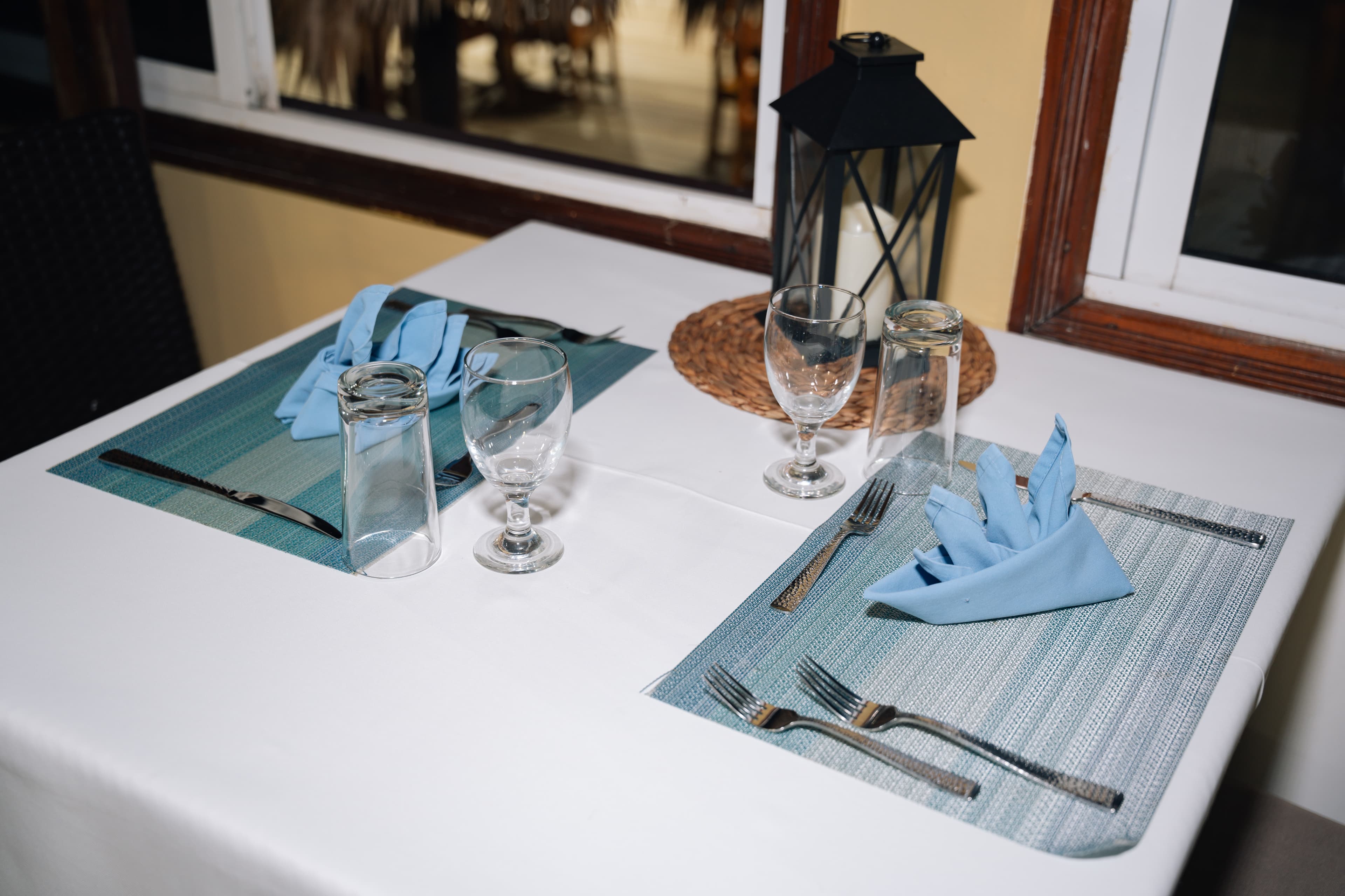 A neatly set dining table with blue napkins, glassware, and silverware.