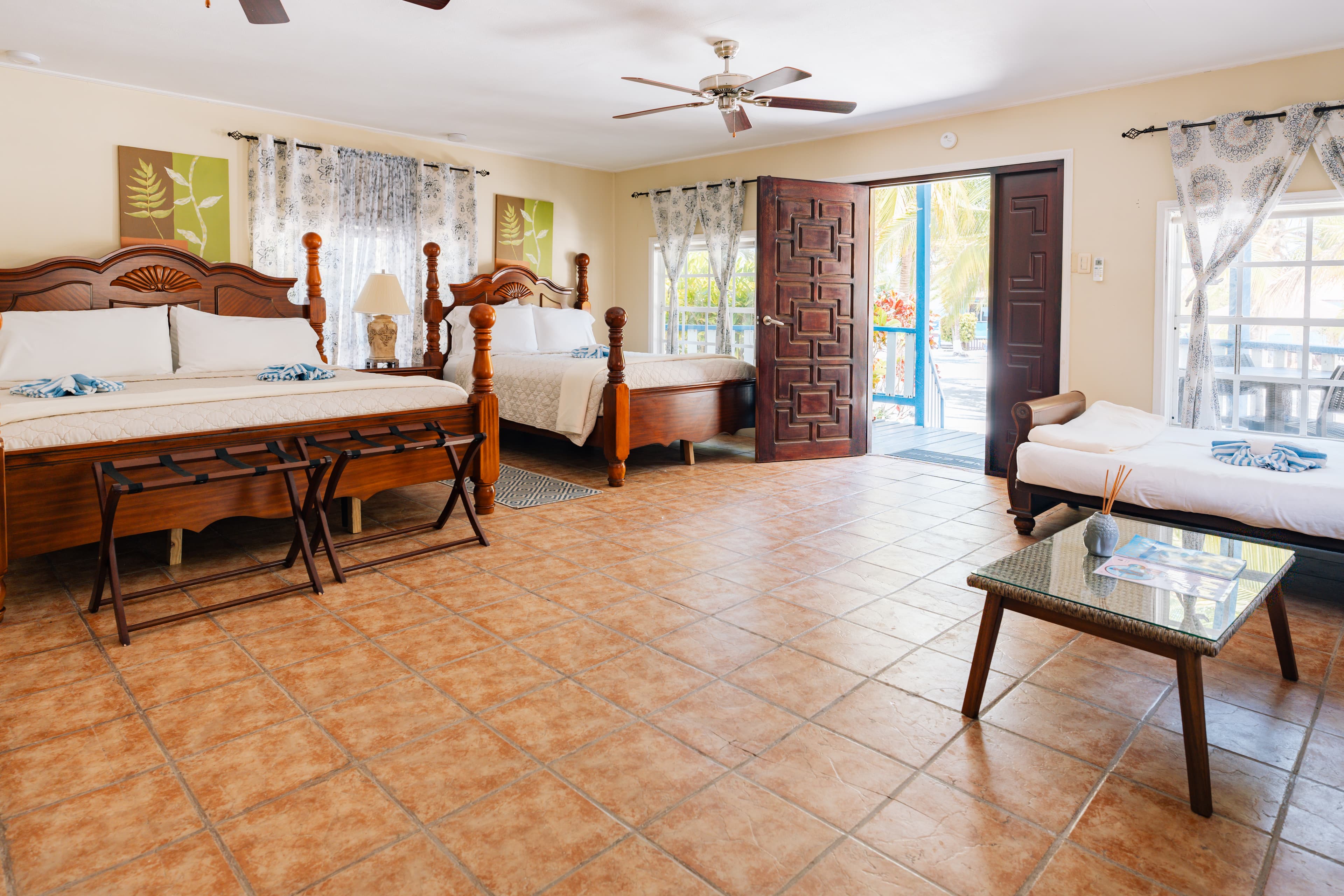 Spacious hotel room featuring two beds, a bedside table, and an open door leading to an outdoor area.