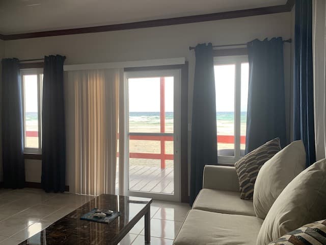 A cozy living room with a view of the beach through sliding glass doors.