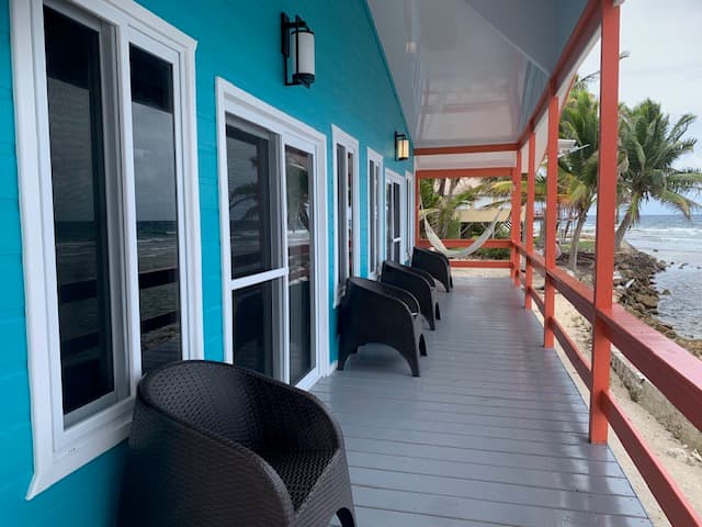 A colorful beachfront porch with black chairs and ocean views.