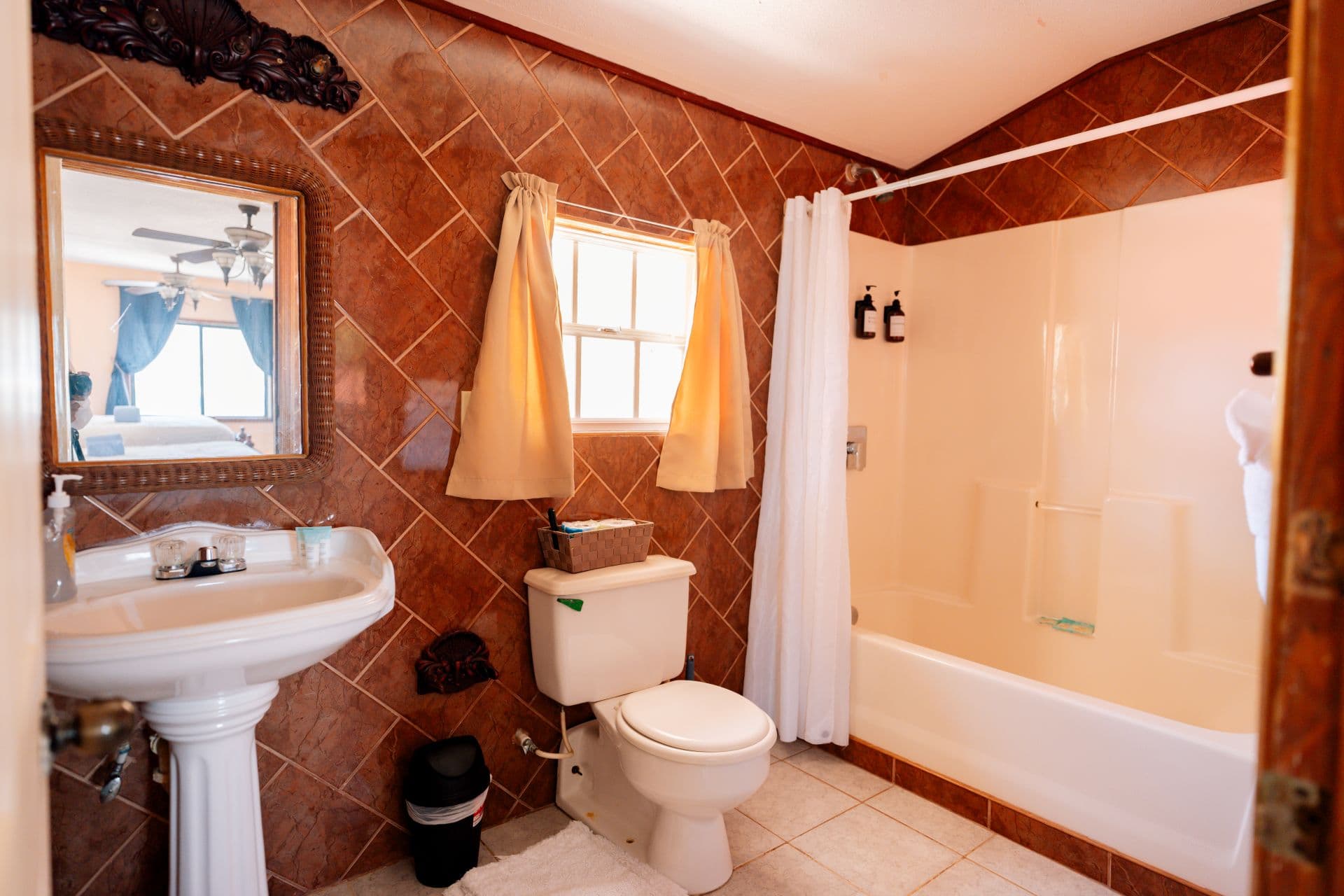 A warm-toned bathroom featuring a sink, toilet, and a shower with a curtain.