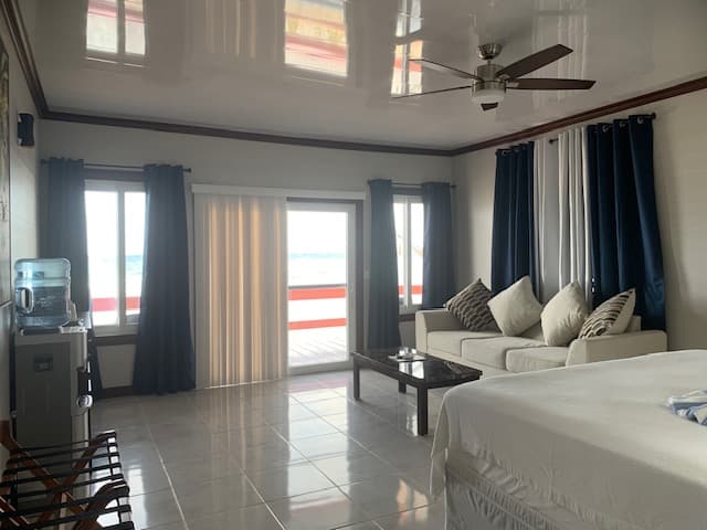 A brightly lit, modern room featuring a sofa, coffee table, and large windows with curtains.
