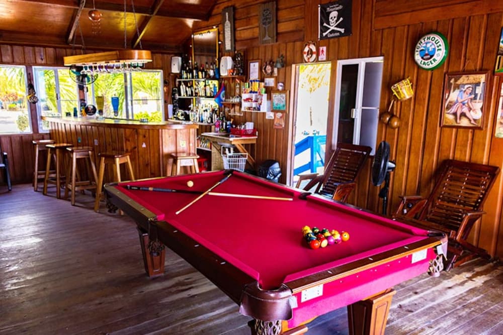 A cozy bar interior featuring a red pool table and wooden decor.