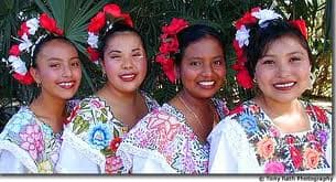Several women wearing white dresses adorned with colorful embroidery
