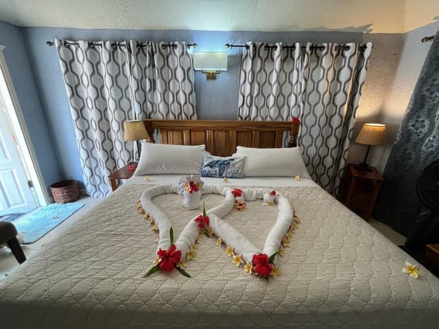 towel art on a bed rolled into a heart, with rose petals on the bed