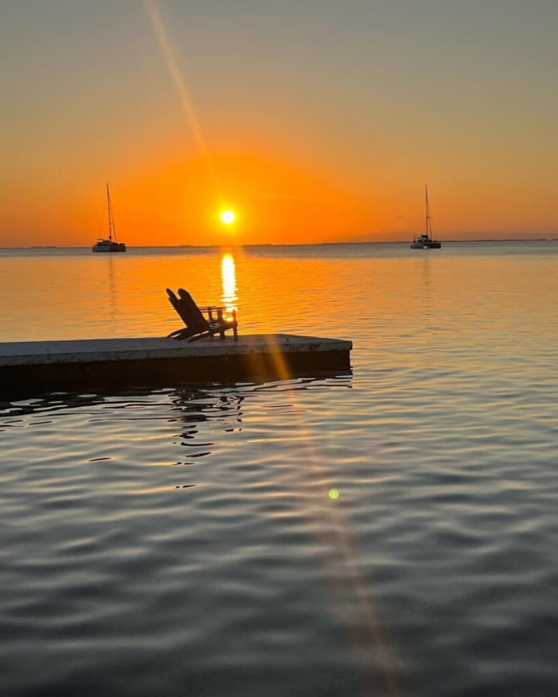 A dock over the water with chairs at sunset. A dock over the water with chairs at sunset.
